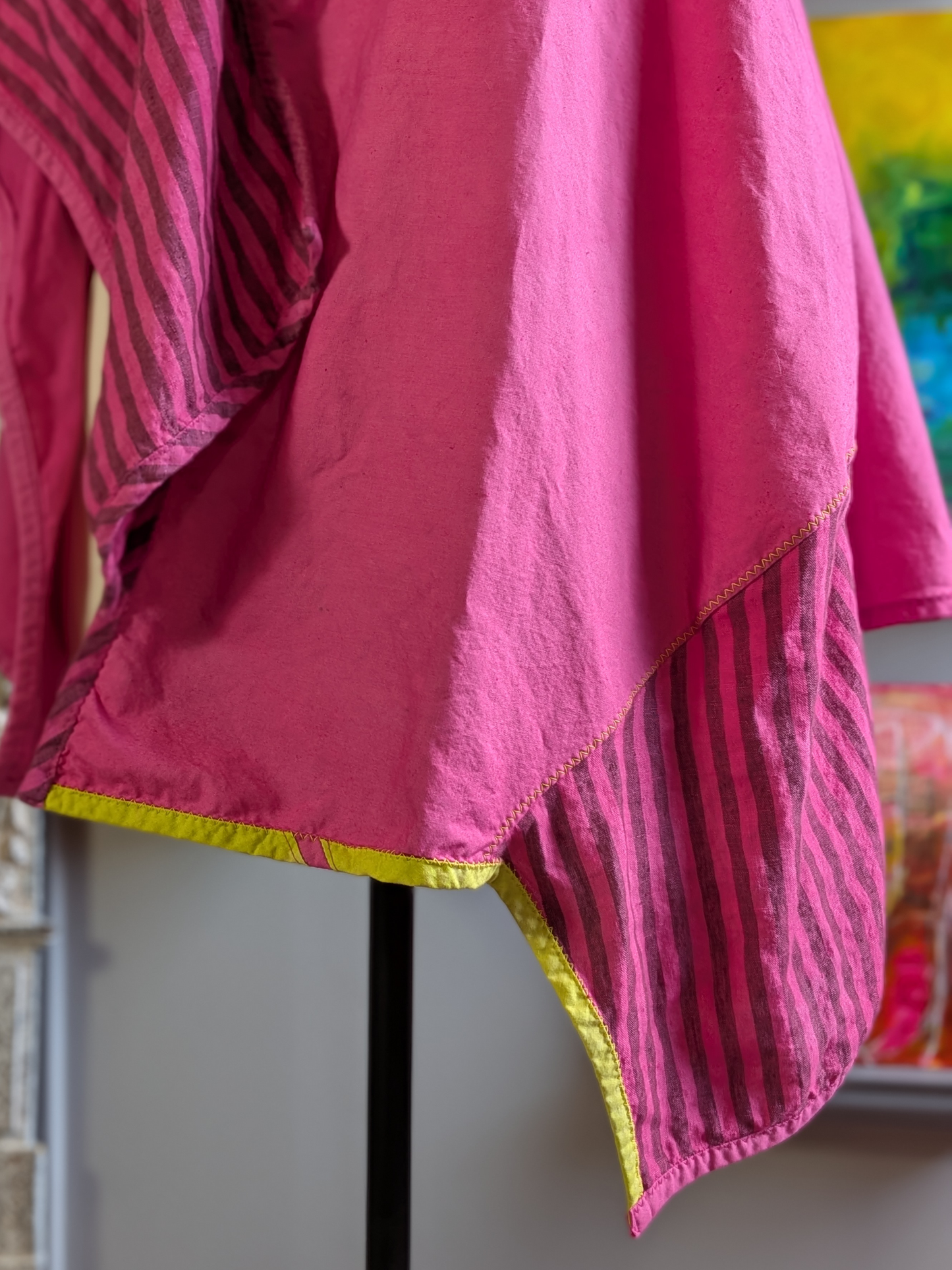 Pink fabric with acid green trim on a stand against a colorful background