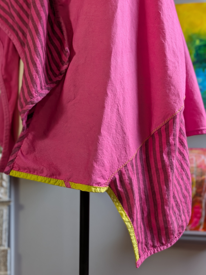 Pink fabric with acid green trim on a stand against a colorful background
