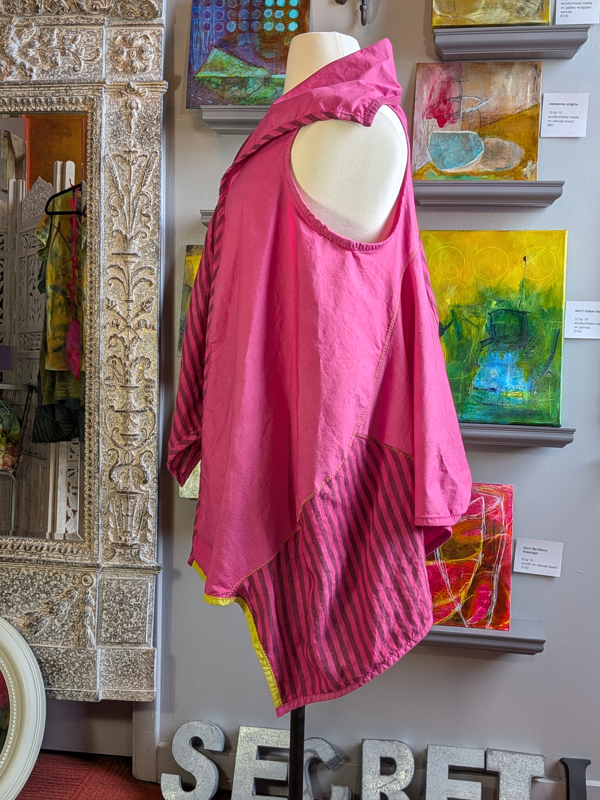 Mannequin wearing a pink garment with abstract art in the background
