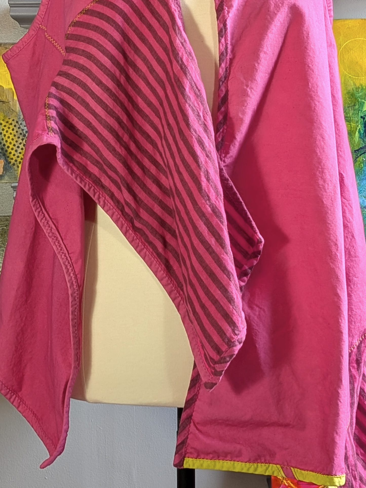 Pink garment with a striped pattern on a mannequin against a colorful background