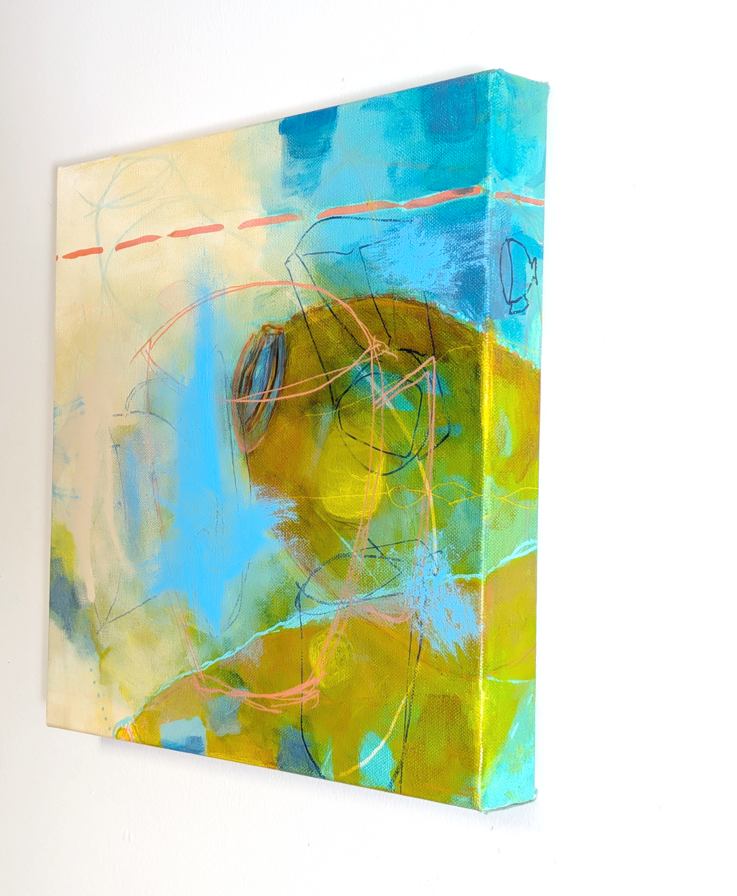 An abstract canvas painting featuring vibrant blue, yellow, and green brushstrokes with delicate orange line details, shown hanging on a plain white wall.