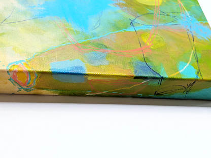 helen carter paitning. Close-up of a colorful abstract canvas painting showing textured brushstrokes in yellow, green, blue, and orange with thin black sketch lines, resting on a white surface.