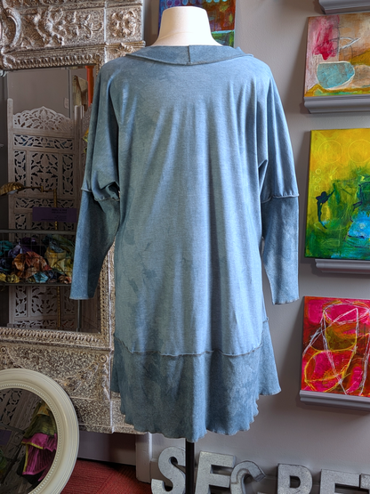 Blue dress on a mannequin against a wall with colorful abstract paintings