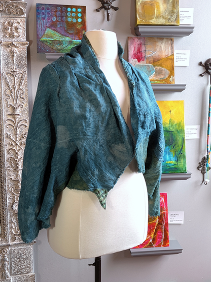 Mannequin wearing a teal textured linen jacket with colorful abstract paintings in the background. secret lentil