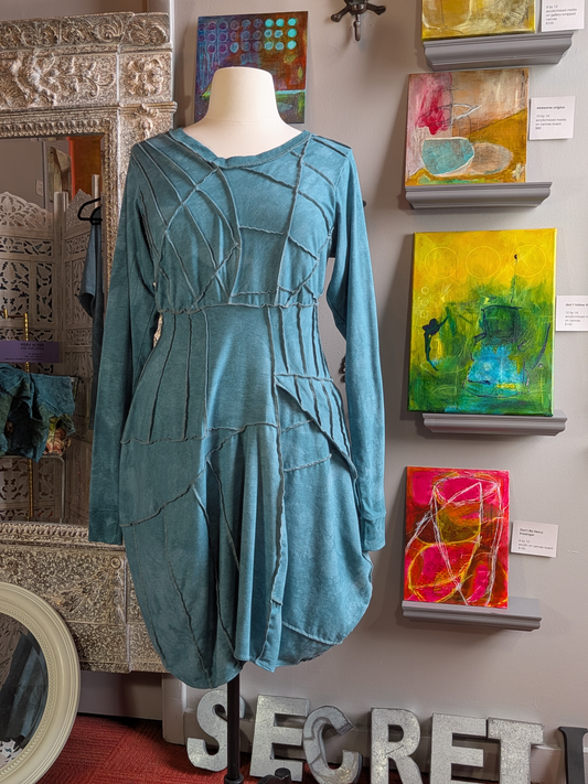 Teal dress on a mannequin in front of wall art with 'Secret Lentil' branding.